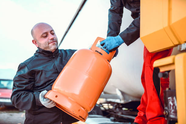 colleagues loading gas cylinder on to tanker truck